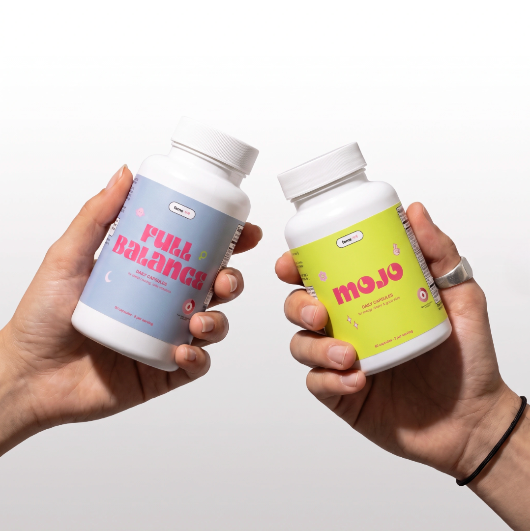Two hands holding Feme Full Balance and Mojo bottles